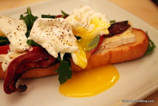 Open-Face Bacon and Egg Sandwich with poached eggs, applewood bacon, and brie cheese on a toasted baguette