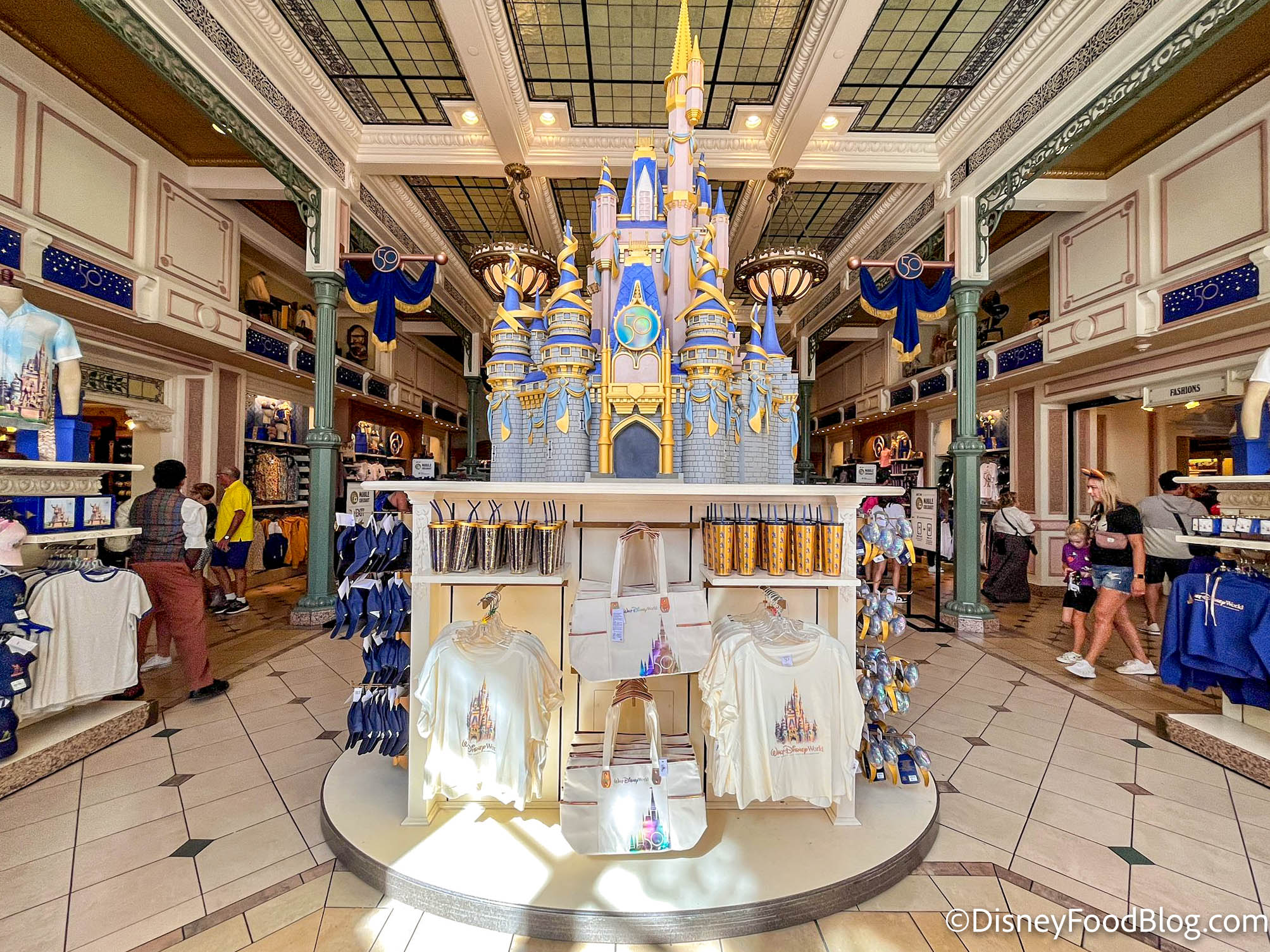 https://www.disneyfoodblog.com/wp-content/uploads/2022/10/2022-wdw-mk-magic-kingdom-emporium-cinderella-castle-merchandise-display-2.jpg